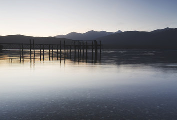 An old wooden pier captured during sunset, the wooden pier was reflected on calm water.