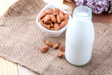 Almond milk in glass bottle on wood background