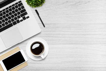 White wood office desk table with laptop, smartphone, cup of coffee and supplies. Top view with...