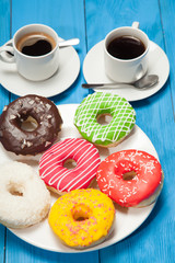Two cups with coffee and donuts on a blue wooden table