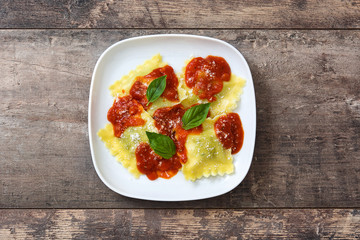 Ravioli with tomato sauce and basil on wooden background. Top view

