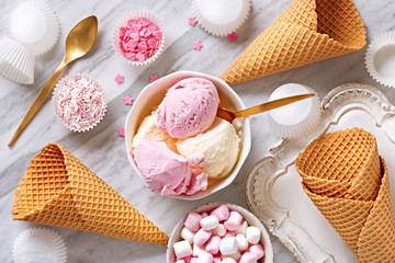 Ice cream ingredients view from above on a marble background. Ice cream in a bowl, ice cream cones,...