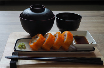 California maki roll in square plate Japanese style served with shoyu sauce and wasabi on table wood