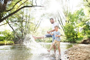 Young father with little boy in the river, sunny spring day.