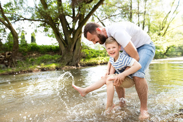 Young father with little boy in the river, sunny spring day.