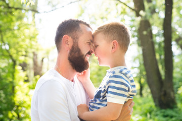 Fototapeta premium Young father with little son in green woods, sunny day.