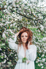 Red-haired girl with freckles near the apple tree