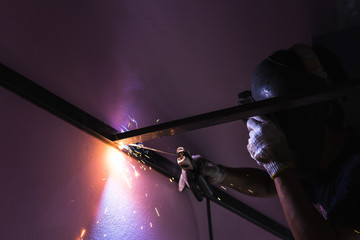 close up worker welding metal with blue arc spark