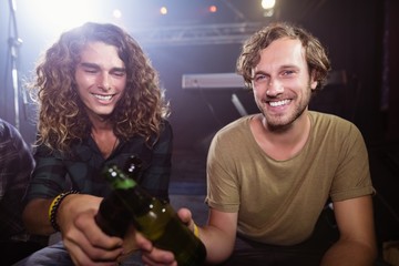 Portrait of smiling male friends toasting beer bottles