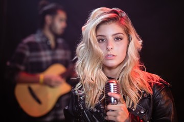Naklejka premium Portrait of female singer holding mic at nightclub