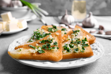 Tasty bread slices with garlic and herbs on plate
