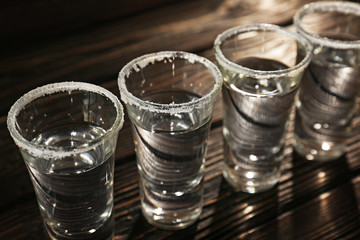 Row of tequila shots on wooden background