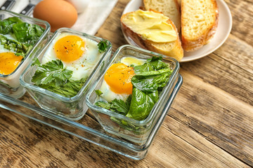 Delicious eggs Florentine in glass baking dishes on wooden table