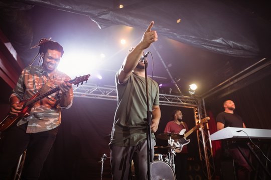 Male singer with musicians performing on stage at nightclub