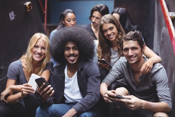 friends using mobile phones on steps at nightclub