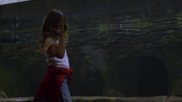 Little Girl Stands In Front Of Aquarium Tank She Picks Her Nose And Eats A Booger