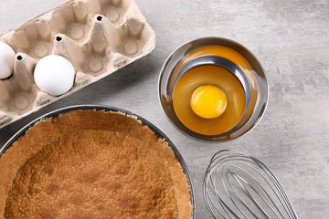 Baking pan, eggs and whisk on kitchen table