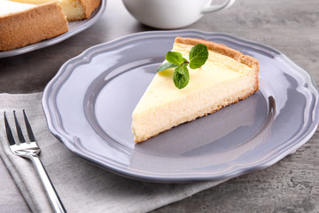Plate with piece of tasty cheesecake on kitchen table, closeup