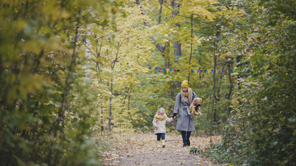 Fototapeta premium Mother and her daughter little girl walking in a autumn park