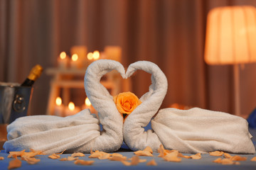 Two swans made of towels and rose petals on bed in hotel room. Honeymoon concept © Africa Studio