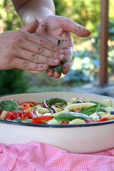 Putting parsley in a bowl of Greek salad. Selective focus.
