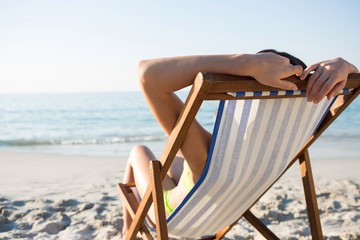 Woman resting on lounge chair at beach