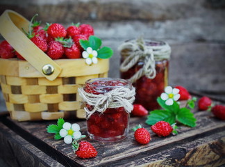 jam from wild strawberries, fresh berries and flowers on wooden Board