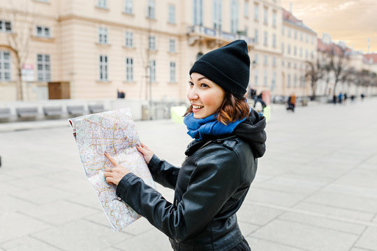Happy woman in casual is guided by a map in the center of a Vienna city, the concept of travel