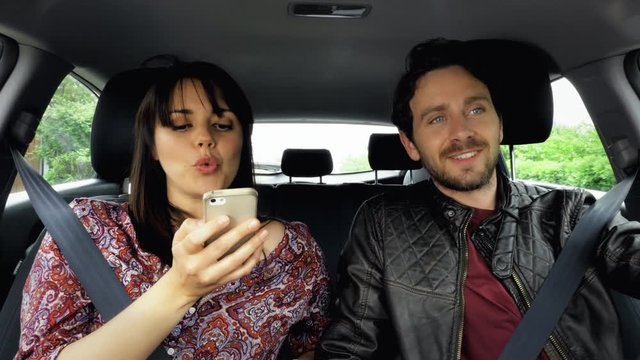 Cute couple talking on phone in car laughing