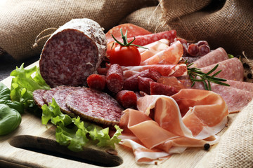 Food tray with delicious salami, pieces of sliced ham, sausage, tomatoes, salad and vegetable - Meat platter with selection