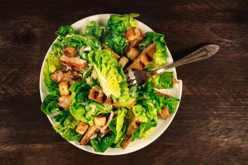 Chicken Caesar salad on rustic background with copyspace