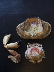 Naklejka premium Whole brown crab separated into parts: Crab claws, crab shell and its brown meat and the body of the crab. Isolated on black background