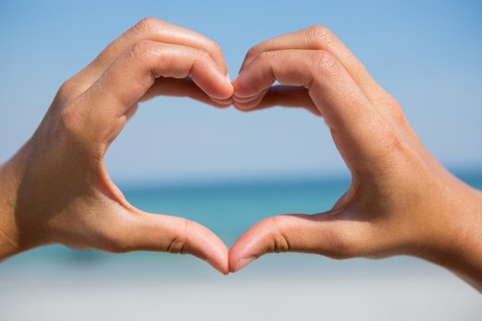 Hands making heart shape at beach