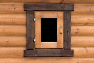 Fototapeta na wymiar Window on the wall of a wooden house from calibrated logs