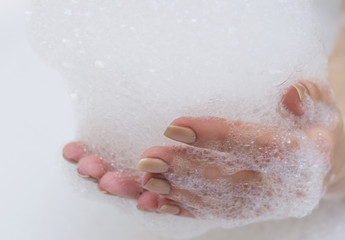 Fototapeta premium Beautiful female hands in white soap.