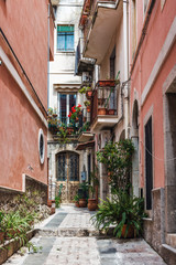 Fototapeta na wymiar Narrow cobbled lane between red walls, Taormina