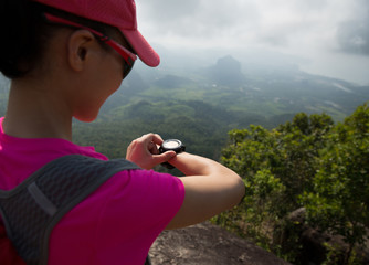young womanhiker checking the altimeter on seaside mountain peak