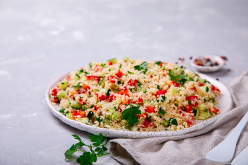 Tabbouleh salad with couscous on the plate.Traditional middle eastern or arab dish.Vegetarian  with cous-cous,parsley,pepper,cucumber,tomato. Part of middle eastern meze.Food or Healthy diet concept.