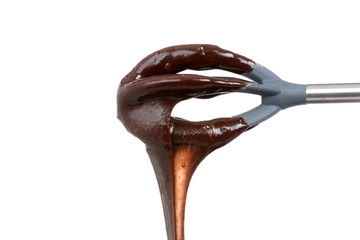 chocolate dripping off a mixing spoon white background