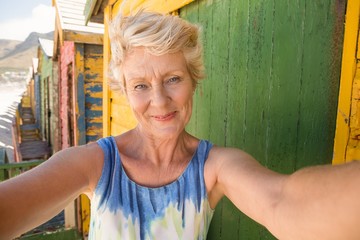 Portrait of smiling senior woman standing against beach hut