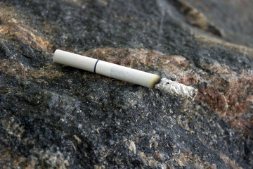 Smokes a cigarette on a granite stone