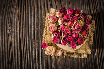 wooden box filled with dried roses on a wooden background