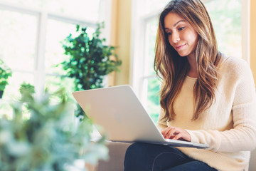 Happy young latina woman using her laptop at home - obrazy, fototapety, plakaty