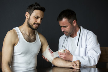 man with bloody wound getting bandage from doctor