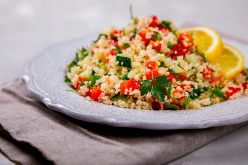 Tabbouleh salad with couscous on the plate.Traditional middle eastern or arab dish.Vegetarian.Parsley,pepper,cucumber,tomato,lemon.Middle eastern meze.Food or Healthy diet concept.Copy space for Text.