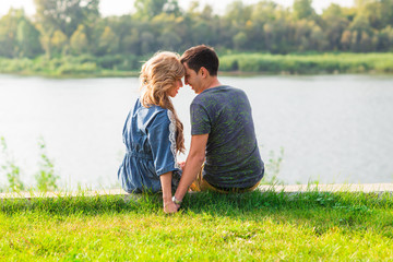 Young love couple sitting on the river bank in summer