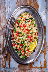 Tabbouleh salad with couscous on the plate.Traditional middle eastern or arab dish.Vegetarian.Parsley,pepper,cucumber,tomato,lemon.Middle eastern meze.Food or Healthy diet concept.Copy space for Text.
