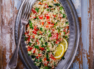Tabbouleh salad with couscous on the plate.Traditional middle eastern or arab dish.Vegetarian.Parsley,pepper,cucumber,tomato,lemon.Middle eastern meze.Food or Healthy diet concept.Copy space for Text.