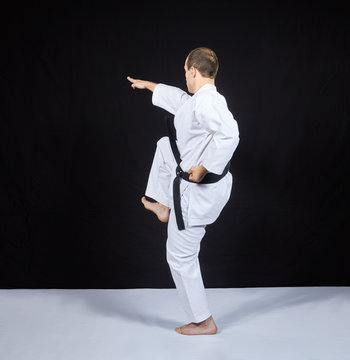 On a black background, a karate athlete beats with a knee