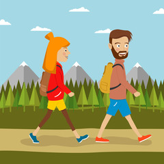 Young couple of hikers with backpacks walking along country road outdoors